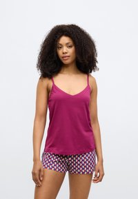 Top magenta sem mangas com alças finas e decote em V, combinado com calções estampados com formas geométricas em roxo, rosa e creme.