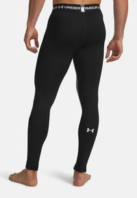 Black athletic leggings with a fitted design, made from stretchy material. Features a branded waistband and a small logo on the lower leg.