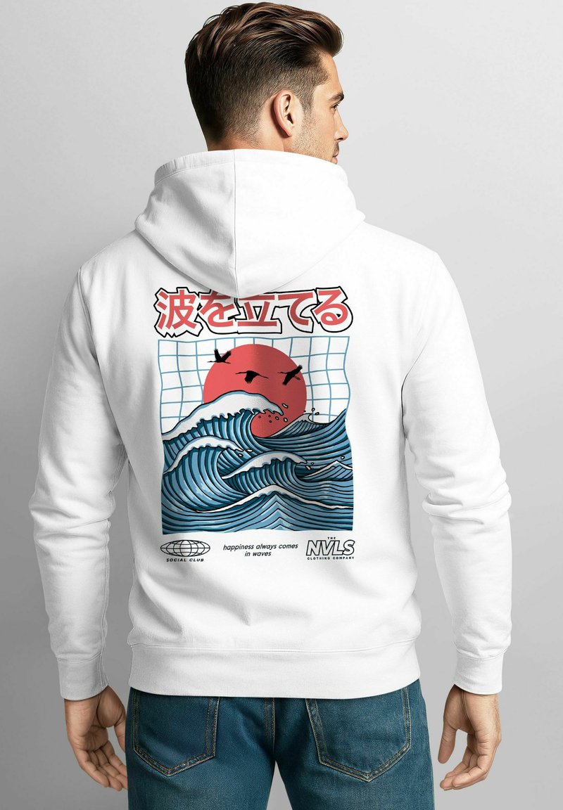 Man in white hoodie displays back graphic of blue ocean waves, red sun, flying birds, and Japanese text with English slogan "happiness always comes in waves."