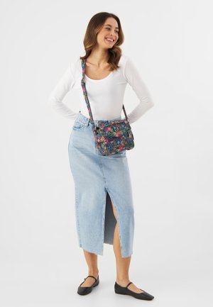 Borsa a tracolla floreale su sfondo nero, con fiori multicolori, tracolla regolabile e due tasche frontali. Gonna di jeans con spacco.