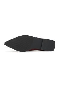Zapato de salón rojo de tacón alto con punta afilada y suela de goma negra texturizada, que presenta un empeine de cuero suave y detalles de diseño minimalistas.