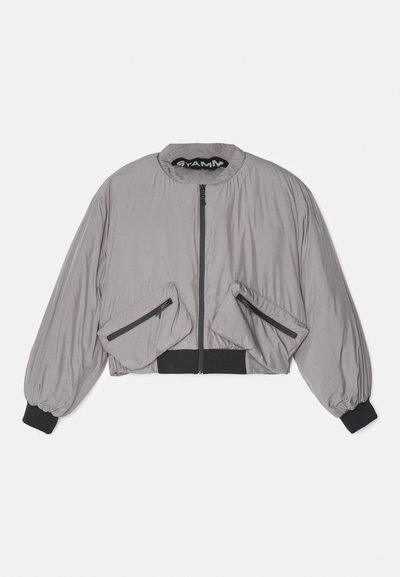 Skraćena siva bomber jakna s patentnim zatvaračem, oversized rukavima i dva prednja džepa s crnim patentnim zatvaračima. Završena crnim rebrastim rubom.