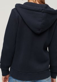 Felpa blu navy realizzata in materiale morbido, con un ampio cappuccio, polsini a costine e un orlo flessibile. Design semplice e pulito senza loghi visibili.