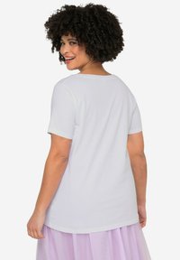 Hvid kortærmet T-shirt med rund halsudskæring, glat tekstur og en afslappet pasform, parret med en lys lavendelfarvet tylskørt.