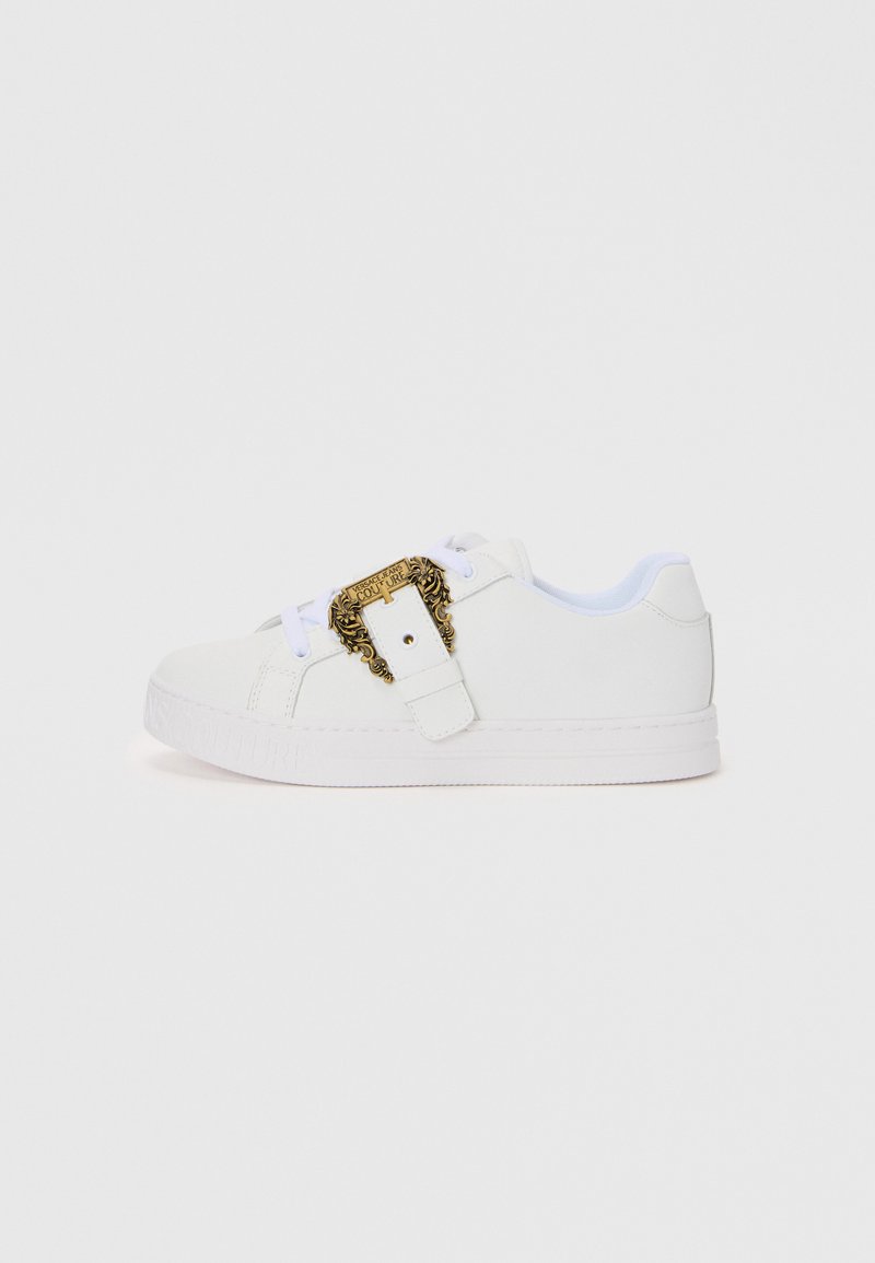 White sneaker with a smooth texture, featuring a gold decorative buckle and brand detail on the side; flat sole and lace closure design.