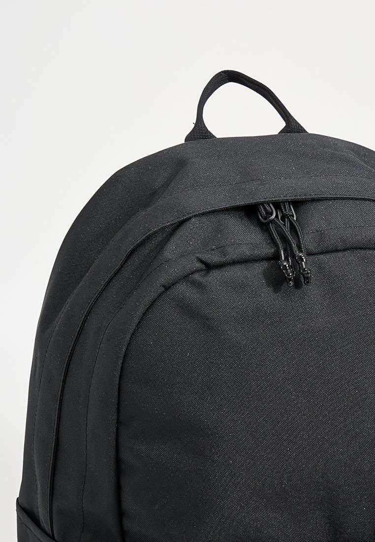 Czarny plecak wykonany z fakturowanej tkaniny o zaokrąglonym kształcie, z uchwytem u góry i podwójnym zamkiem błyskawicznym w głównym komorze.