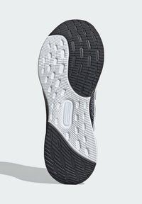 Semelle de chaussure avec un dessous en caoutchouc noir texturé et des zones blanches à motifs, offrant adhérence et stabilité sur diverses surfaces.
