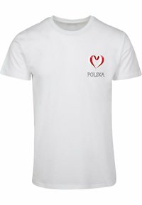 Valge T-särk, millel on punane ja valge südamekujundus ning sõna "POLSKA" musta teksti all graafika all. Lühikesed varrukad, puuvillane materjal.