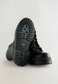 Czarne skórzane buty z grubą podeszwą, okrągłym noskiem i sznurowanym designem. Posiadają kontrastowe szwy oraz logo na podeszwie. Guma na podeszwie.