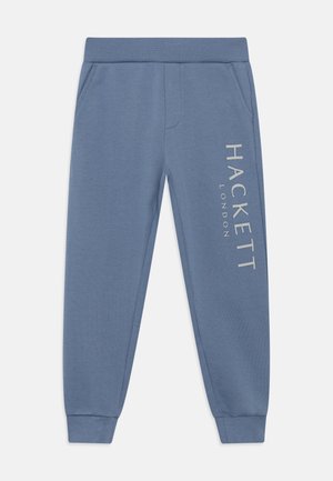 Blue sweatpants made of soft fabric, featuring side pockets, ribbed cuffs, and white printed text "HACKETT LONDON" on the left leg.
