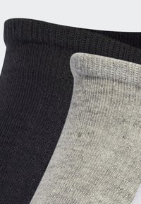 Sorte og grå ribbede sokker med en tyk manchet og tekstureret overflade, vist side om side, som fremhæver de kontrasterende farver og mønstre.