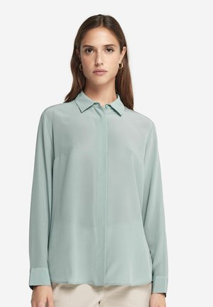Blouse légère verte à manches longues en tissu transparent. Présente un col classique, une fermeture boutonnée à l'avant et des poignets boutonnés. Texture lisse.
