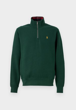 Grøn sweatshirt med høj hals og lynlås, ribbede manchetter og kant. Har et lille gult logo på brystet og en rødternet foring indeni kraven.