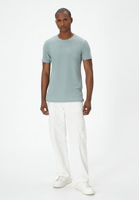 Himmelblå kortærmet t-shirt lavet af blødt stof, parret med hvide cargobukser. Sneakers har et minimalistisk design og en hvid farve.