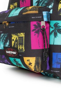 Batoh Eastpak z černé textilie s multicolorovými grafickými potisky. Má přední zipovou kapsu a značkovou nášivku. Texturovaný povrch.