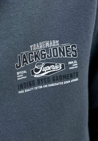 Tissu bleu foncé avec un texte blanc indiquant Jack & Jones Superior et un texte plus petit supplémentaire sur le denim et le coton.