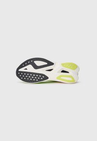 Sko såle med svart gummi, grønne detaljer og hvite seksjoner. Den har teksturert grep, ventilasjons hull og et asymmetrisk design.