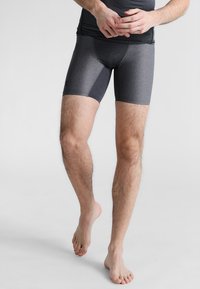 Pantaloni corti sportivi grigi realizzati in tessuto elastico, con un design aderente e una texture liscia. La vita è elasticizzata con un branding minimo.