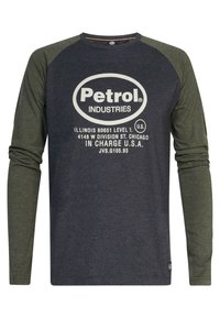Langærmet skjorte med mørkeblå krop og olivengrønne raglanærmer. Har hvid teksttryk, herunder "Petrol Industries."