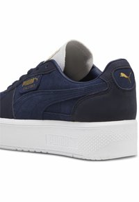 Tengerésznadrág bőr sneaker fehér texturált talppal, arany Puma logóval és részletekkel, valamint párnázott bokarész a kényelemért.