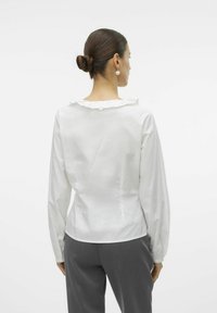 Witte blouse met lange mouwen, een gerimpelde kraag en een getailleerde taille, gemaakt van een glad, lichtgewicht stof en met zacht geplooide mouwen.