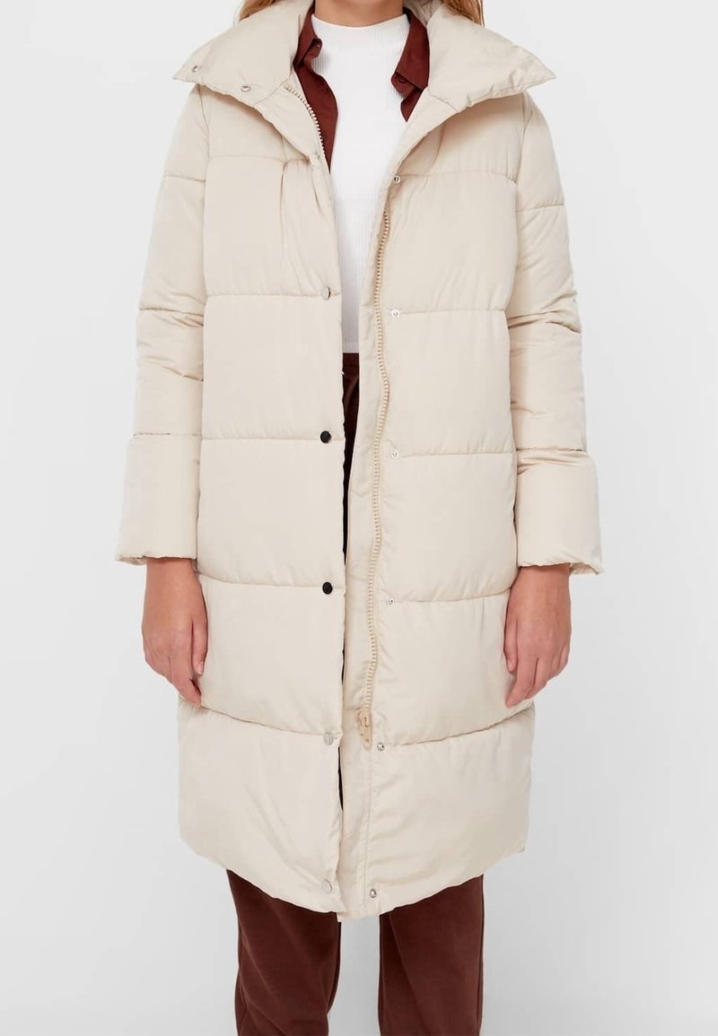 Abrigo tipo puffer beige con capucha, con cierre de cremallera y botón a presión, patrón de acolchado horizontal y bolsillos laterales.