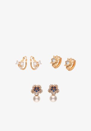 Tre paia di orecchini color oro: cerchi con pietre trasparenti, orecchini a forma di stella con gemme centrali e orecchini floreali con accenti blu e perle pendenti.