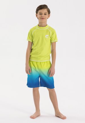 Rash guard verde de manga corta con detalles y logo en blanco, combinado con bañador de gradiente azul a verde, ambos hechos de tejido ligero.