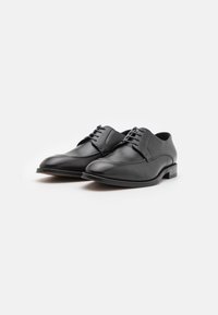 Scarpe eleganti in pelle nera con finitura liscia, punta tonda e quattro occhielli. Presentano un tacco basso e un dettaglio di cucitura sottile.