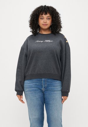 Grå sweatshirt med rund halsringning, med broderad text "Tommy Hilfiger" och gyllene knappar på axeln. Långa ärmar med ribbad mudd.