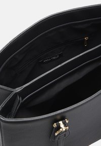 Borsa a mano nera strutturata con texture a granuli, dettagli in hardware dorato e un ampio interno con una tasca con zip.