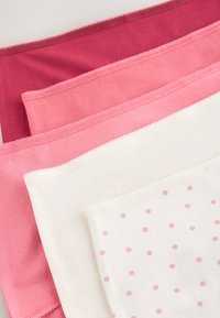 Four folded cotton underwear in burgundy, light pink, white, and white with pink polka dots, stacked diagonally.