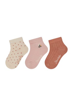 Three pairs of socks: cream with red polka dots, solid pink with a flower detail, and ribbed terracotta. Soft material, ankle height.