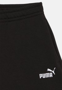 Černé tepláky vyrobené z bavlněné směsi, s elastickým pasem a bílým vyšívaným logem "PUMA" na levé straně.