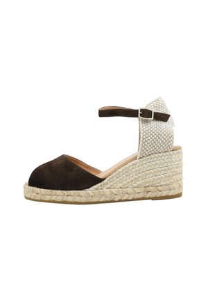 Sandalía de cuña tipo alpargata de ante marrón, con pulsera en el tobillo, talón tejido, puntera cerrada y suela de yute trenzado, mostrada de perfil.