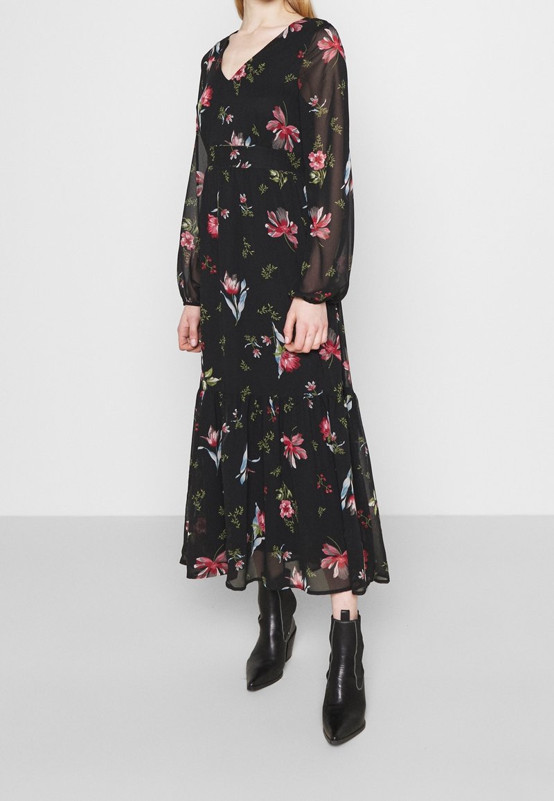 Robe longue noire à fleurs avec de longues manches transparentes, présentant des fleurs multicolores, un décolleté en V, une taille cintrée et un ourlet fluide en étages.