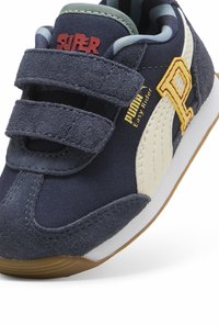 Tumed sinine toss, millel on sametise tekstuuriga pealis, hookus pannud Velcro rihmad, valged aktsendid ja kollane logo. Kummist tald pruuni põhjaga.
