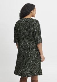 Rochie neagră cu mâneci scurte, având un model floral verde împrăștiat, material moale, tiv mediu și o croială lejeră.