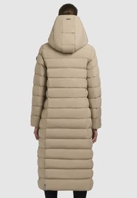 Beige lang puffetjakke med hætte, der har et quiltet design med vandrette striber. Stoffet ser blødt, luksuriøst og isoleret ud.