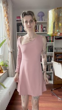 Vestido rosa claro com decote assimétrico e uma manga longa. Feito de um material suave, apresenta uma saia rodada e detalhes mínimos.