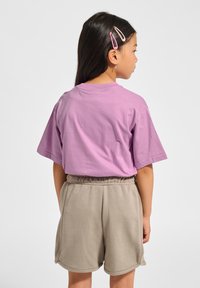 Lila T-Shirt mit kurzen Ärmeln und rundem Ausschnitt, kombiniert mit beigefarbenen Shorts mit elastischem Bund. Glatter Stoff, lässige Passform, keine sichtbaren Muster.