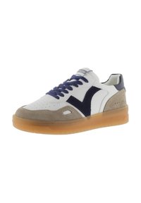 Sneaker bianca e grigia con accenti blu navy, materiali in suede e pelle, punta forata, lacci piatti e suola in gomma semi-trasparente.