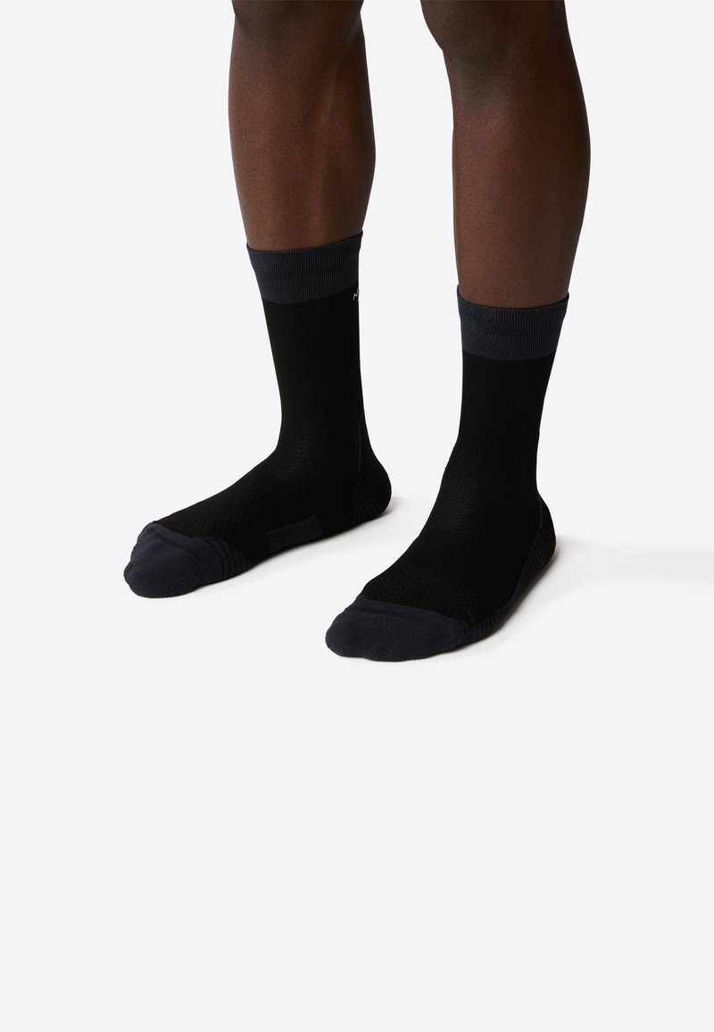 Calcetines negros con acentos azul oscuro en el puño, que presentan un diseño texturizado y áreas de puntera y talón reforzadas.