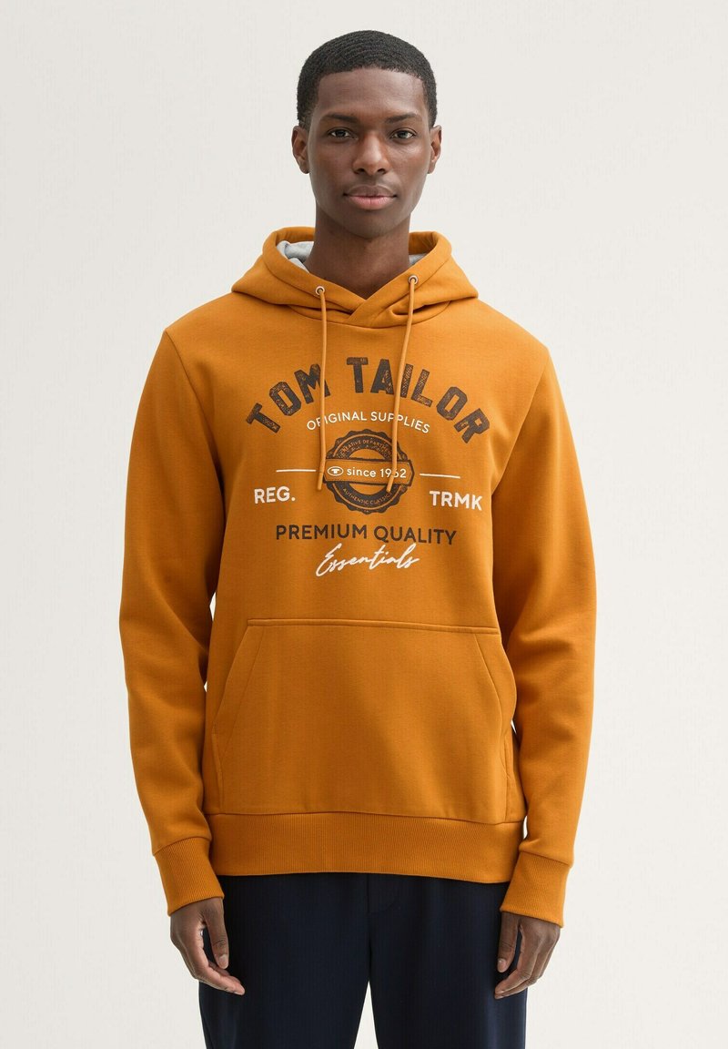 Hanorac portocalie cu glugă, fabricat din material fleece, având o buzunar frontal de tip kangaroo și branding imprimat cu text închis pe piept.