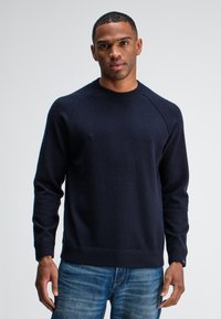 Marineblauwe crewneck sweater met ribgebreide manchetten en zoom, gemaakt van zachte, gestructureerde stof. Beschikt over raglanmouwen voor een ontspannen pasvorm.