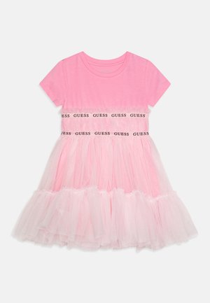 Vestido rosa de manga corta para niña con falda de tul, detalles de volantes y dos bandas horizontales con el logo "GUESS" repetido.