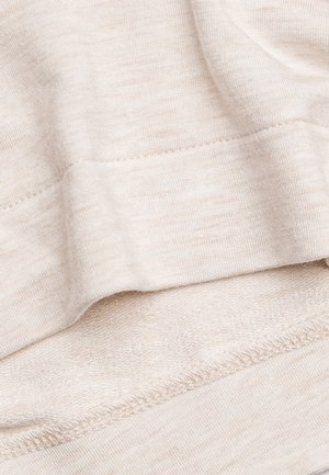 Beige, texturerat tyg med en mjuk, något ribbad yta. Har en slät nederkant och subtila färgvariationer genom hela tyget.