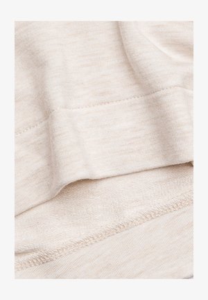 Tessuto beige, texture morbida e leggermente rigata. Presenta un orlo liscio e sottili variazioni di colore in tutto il tessuto.