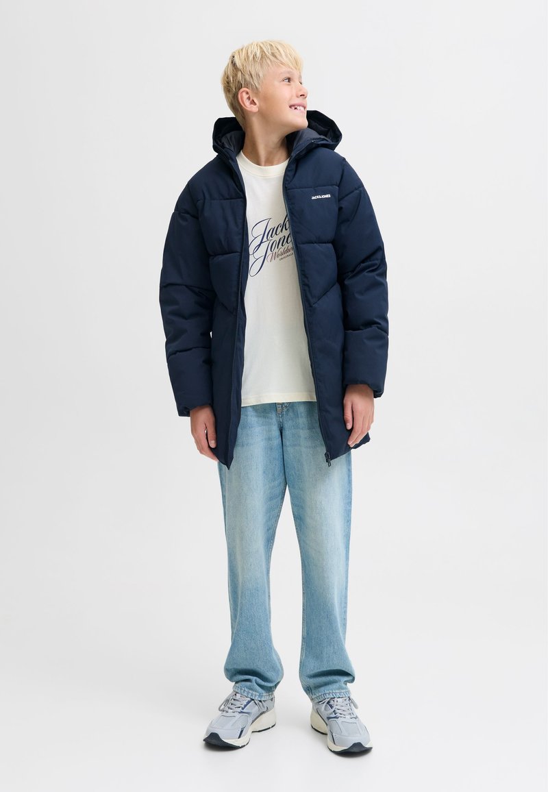 Námořnická prošívaná bunda s kapucí, se zapínáním na zip a prošívanou texturou. Kombinovaná s lehkým tričkem a volnými světlými džínami.