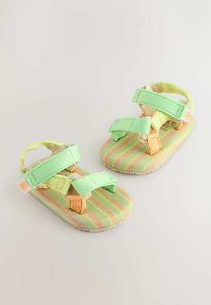 Zelene in oranžne sandale na trak s črtastimi tkaninskimi podplati, ki imajo nastavljive trakove in teksturiran gumo podplat. Lahka zasnova.